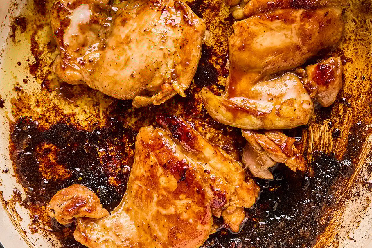 Chicken cooking in a pan on the stove.
