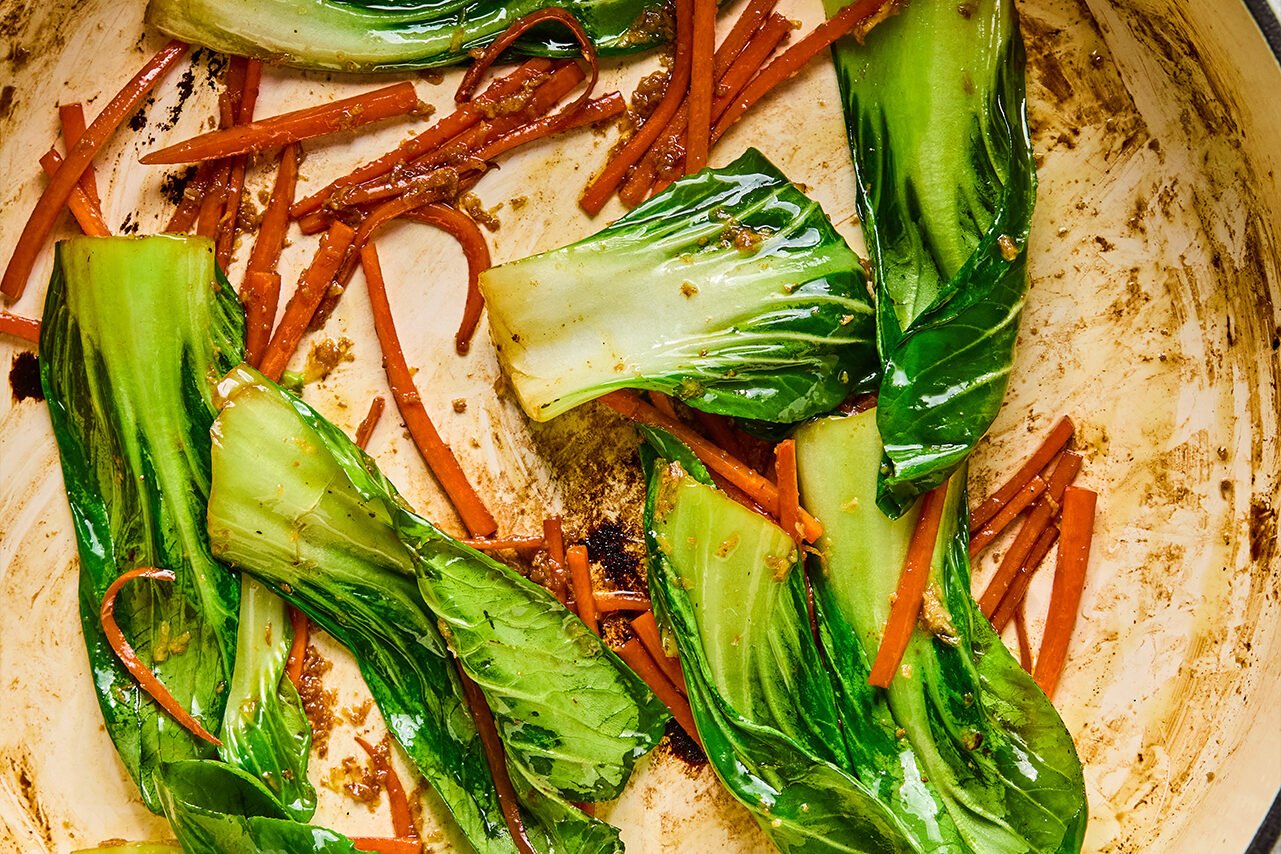 Carrots and baby bok choy sauting in a pan.
