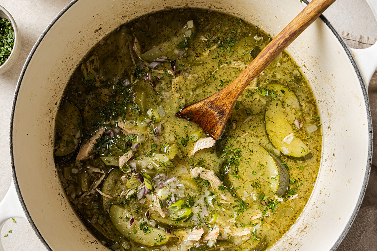 The soup liquid mixing with the sauted vegetables in a Dutch oven.