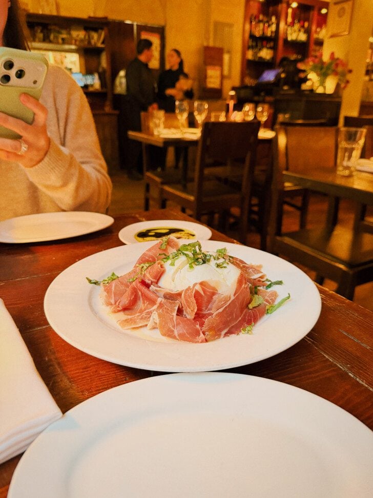 Buffalo mozarella and proscuitto on a plate in a restaurant.