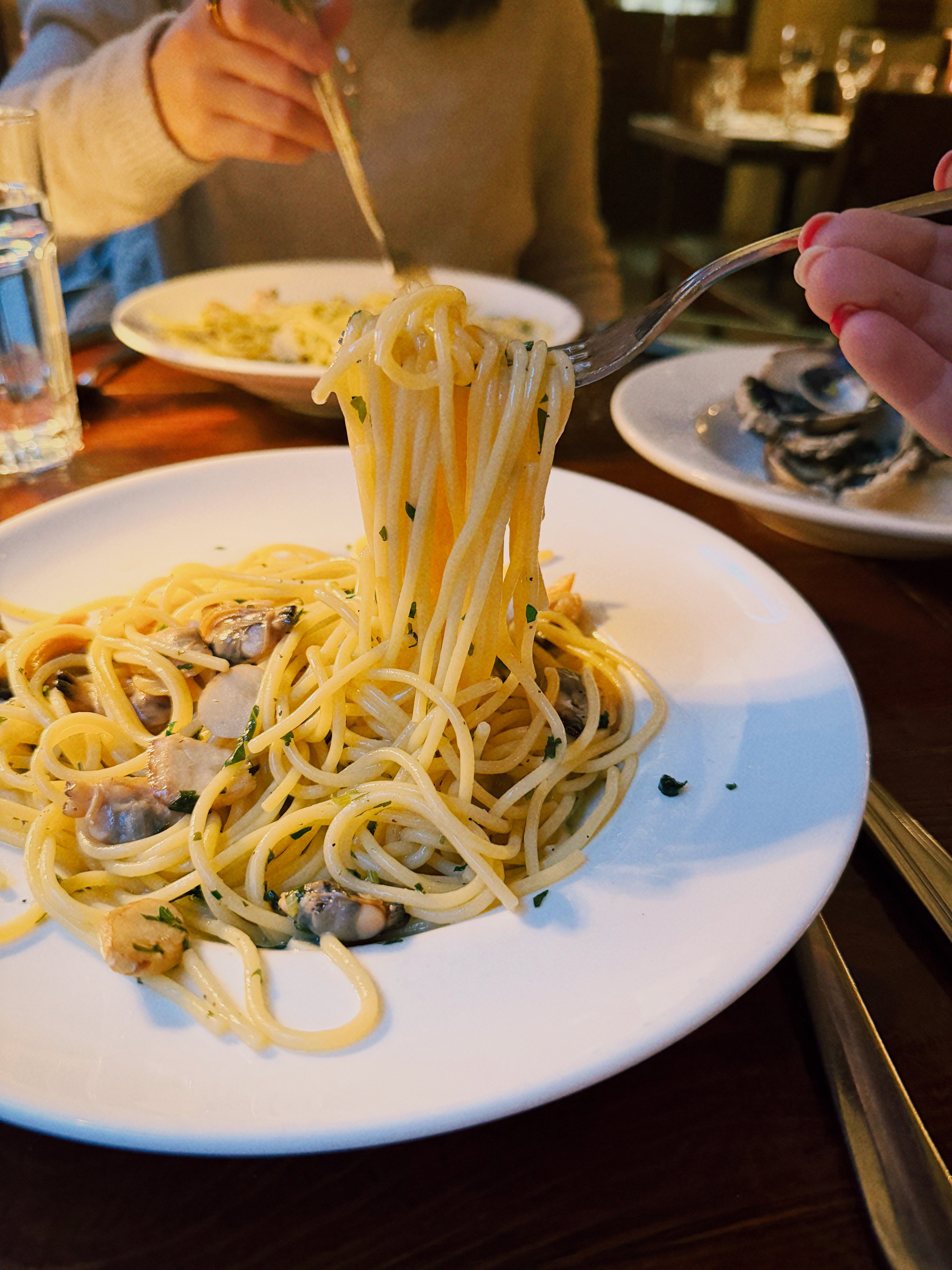 Linguini and clams on a plate with a fork pulling up the pasta.