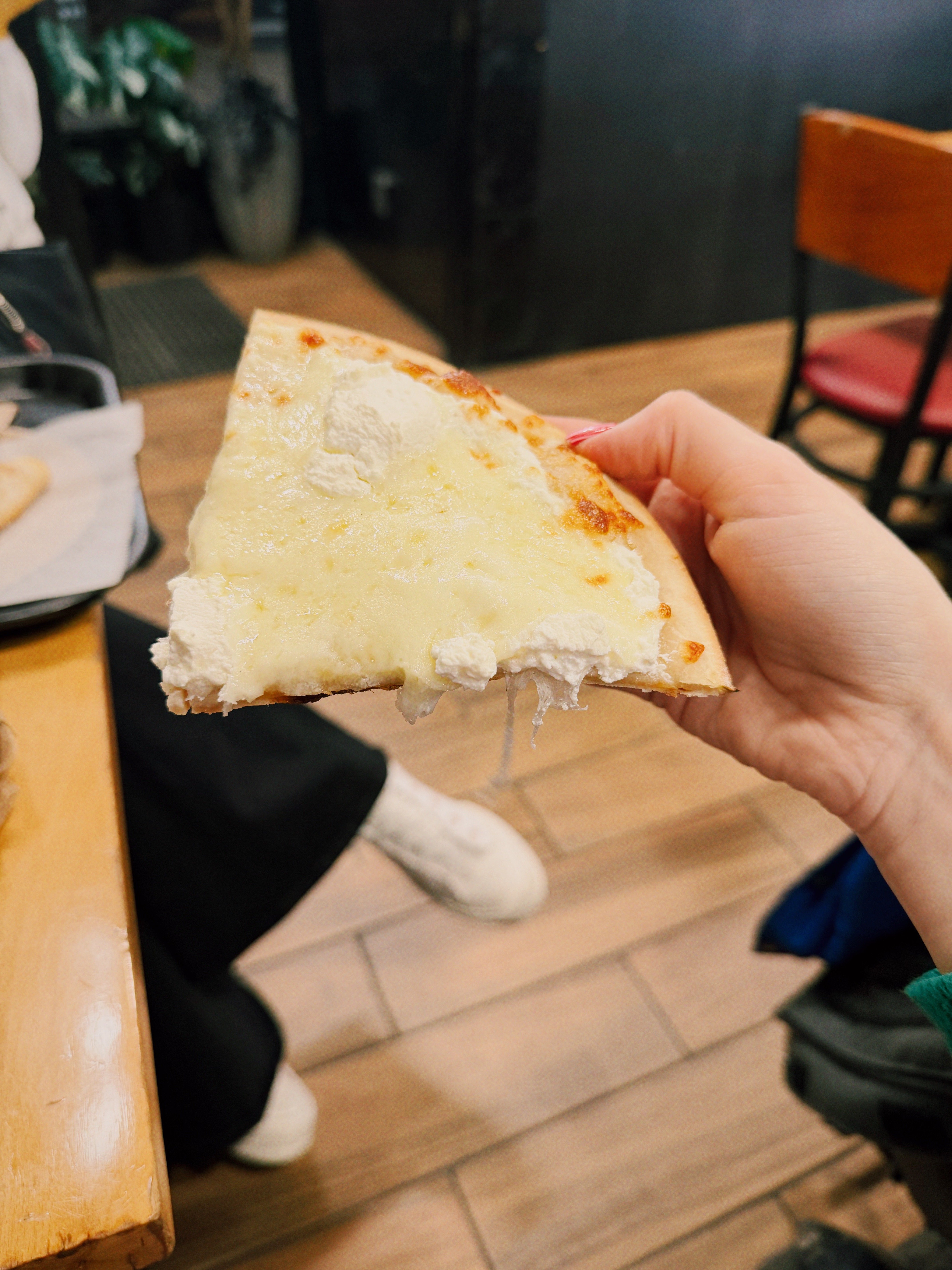 A slice of white pizza being held up.