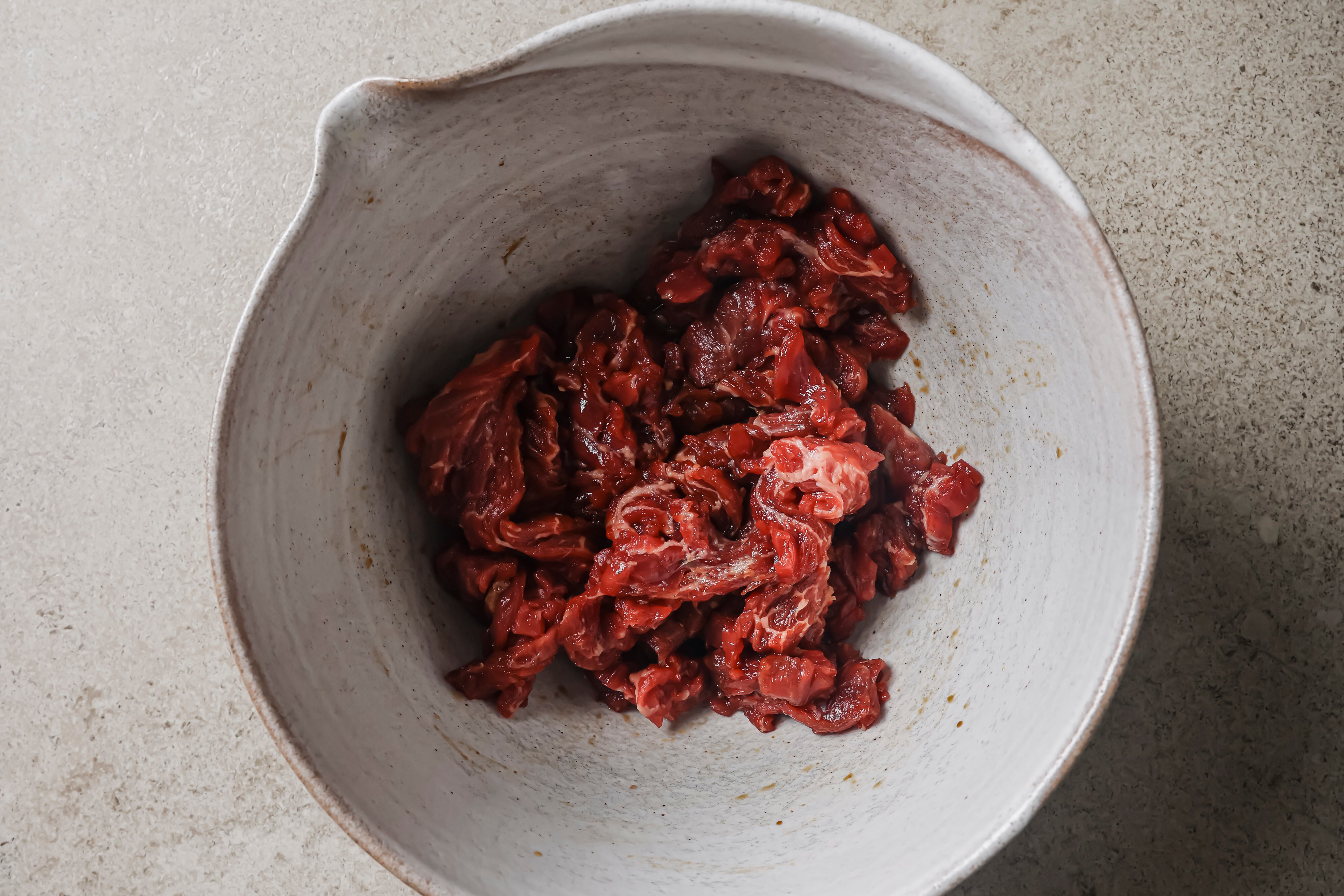 Sliced steak marinating in a bowl.