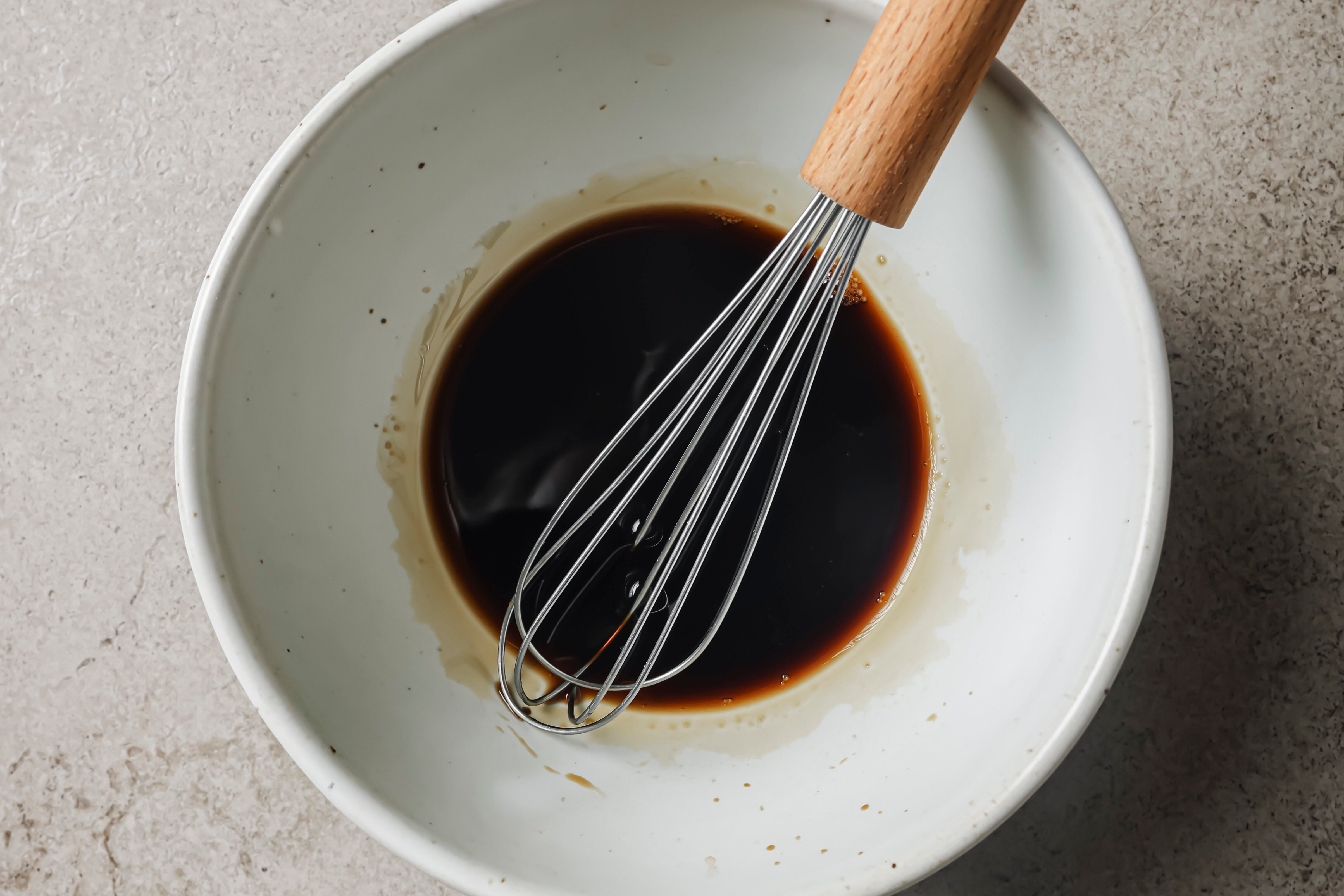 Beef chow fun sauce in a large bowl with a whisk.