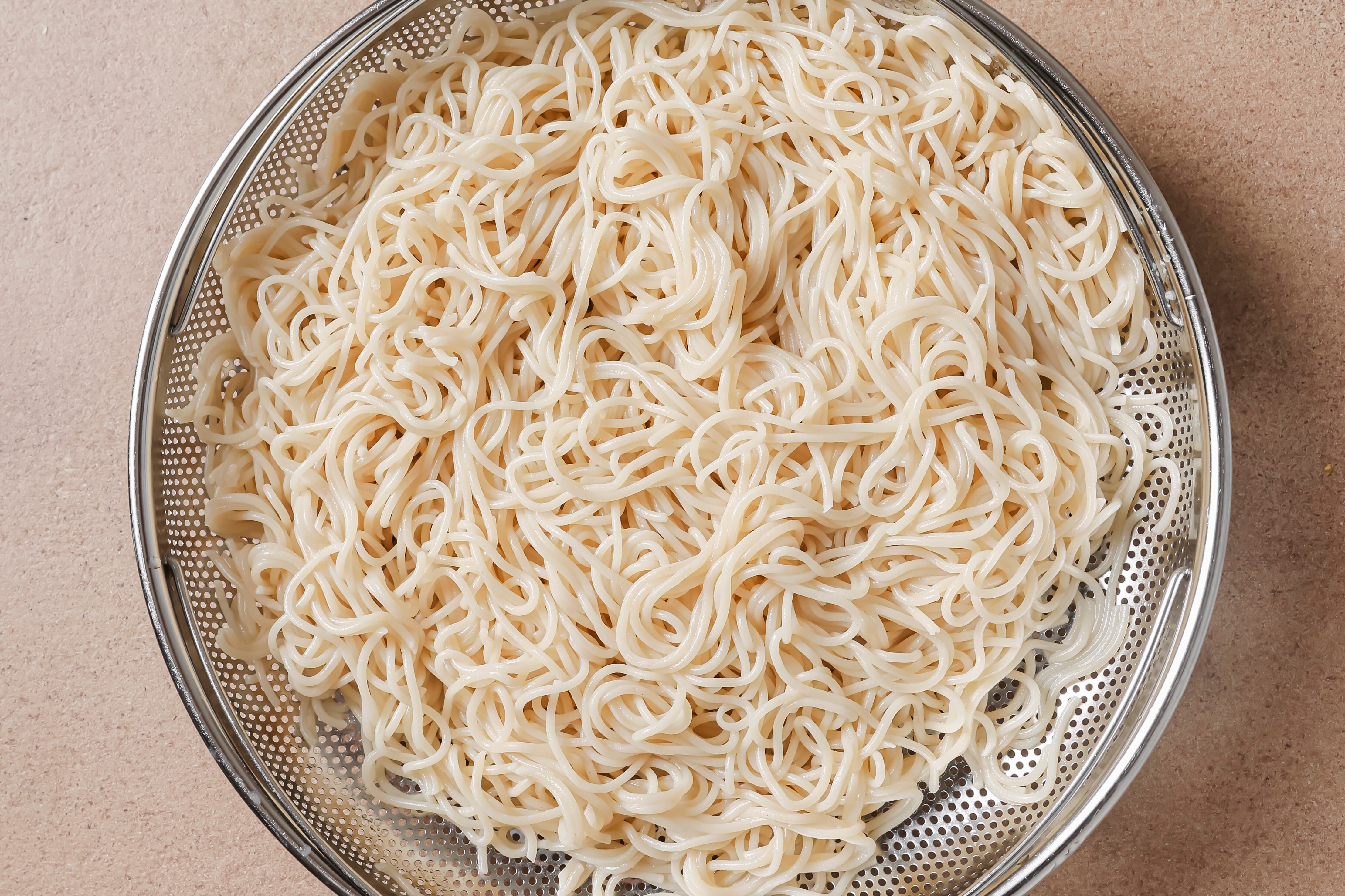 A strainer with cooked ramen noodles in it.