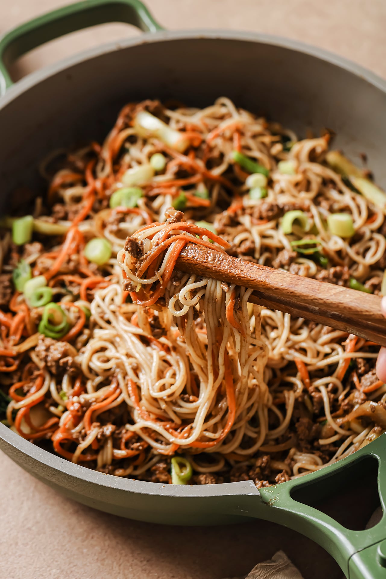 A pan with hoisin beef noodles after cooking and with chopsticks taking a bite out of the pan.