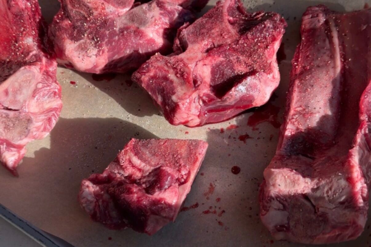 Meaty beef bones on a parchment lined baking sheet.