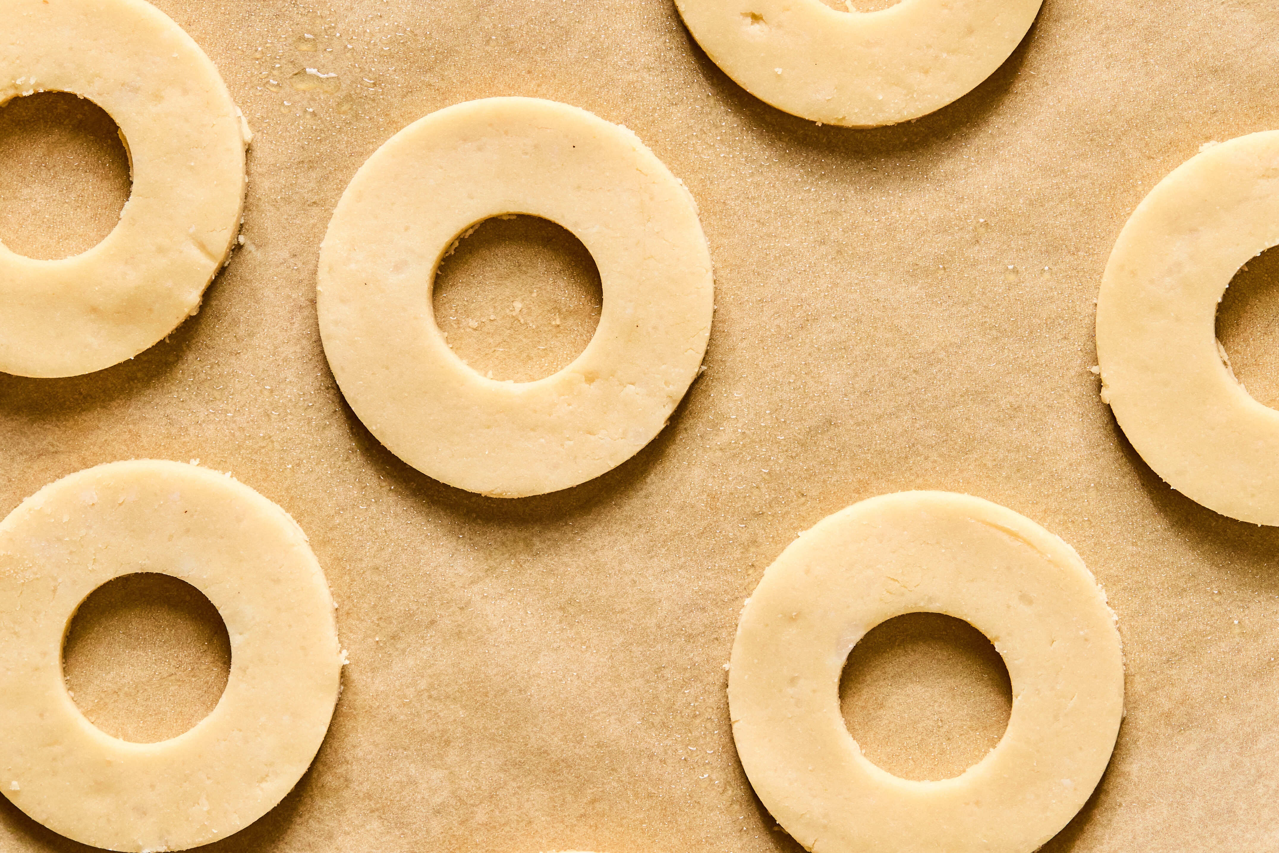 Circular cut outs of dough sitting on a sheet of parchment paper.