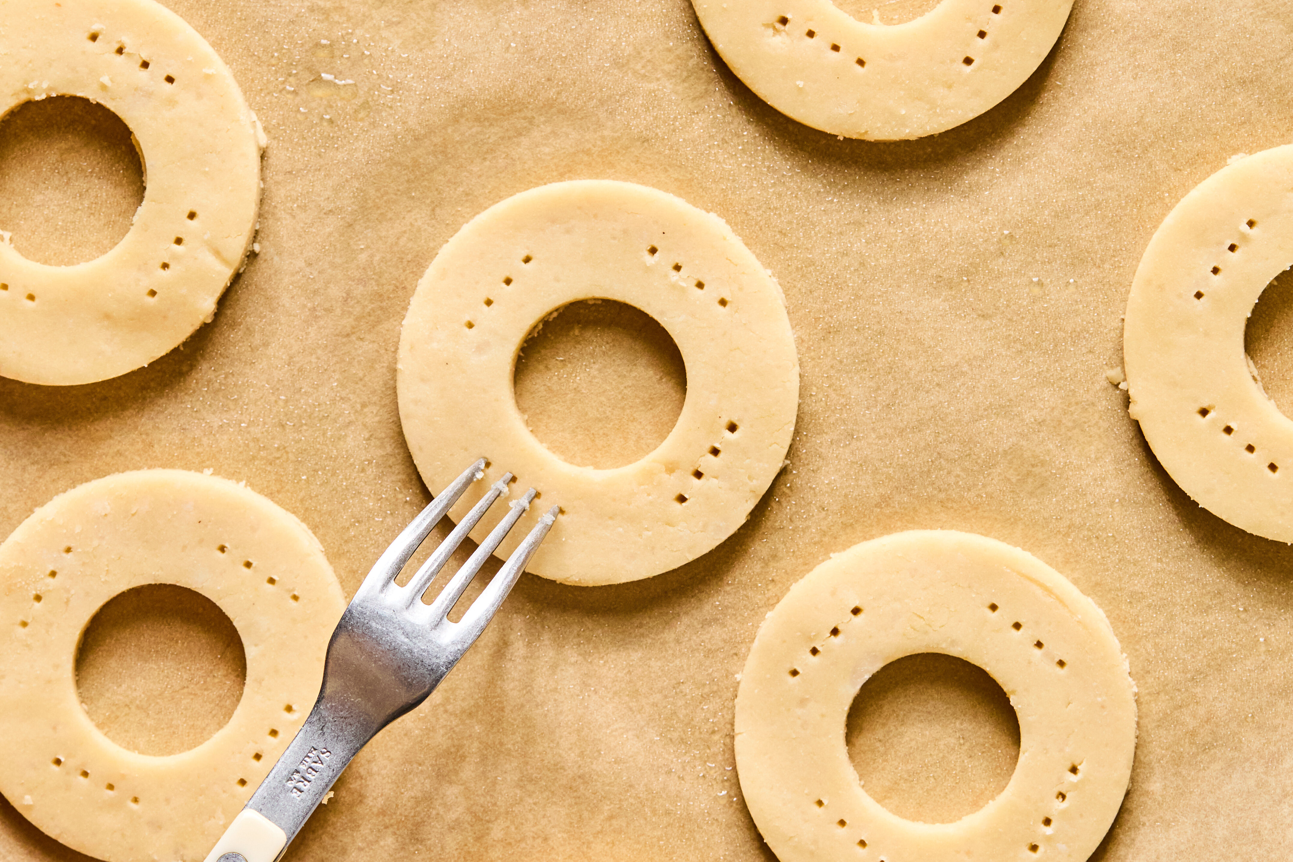 A fork making punctures into the round dough circles.