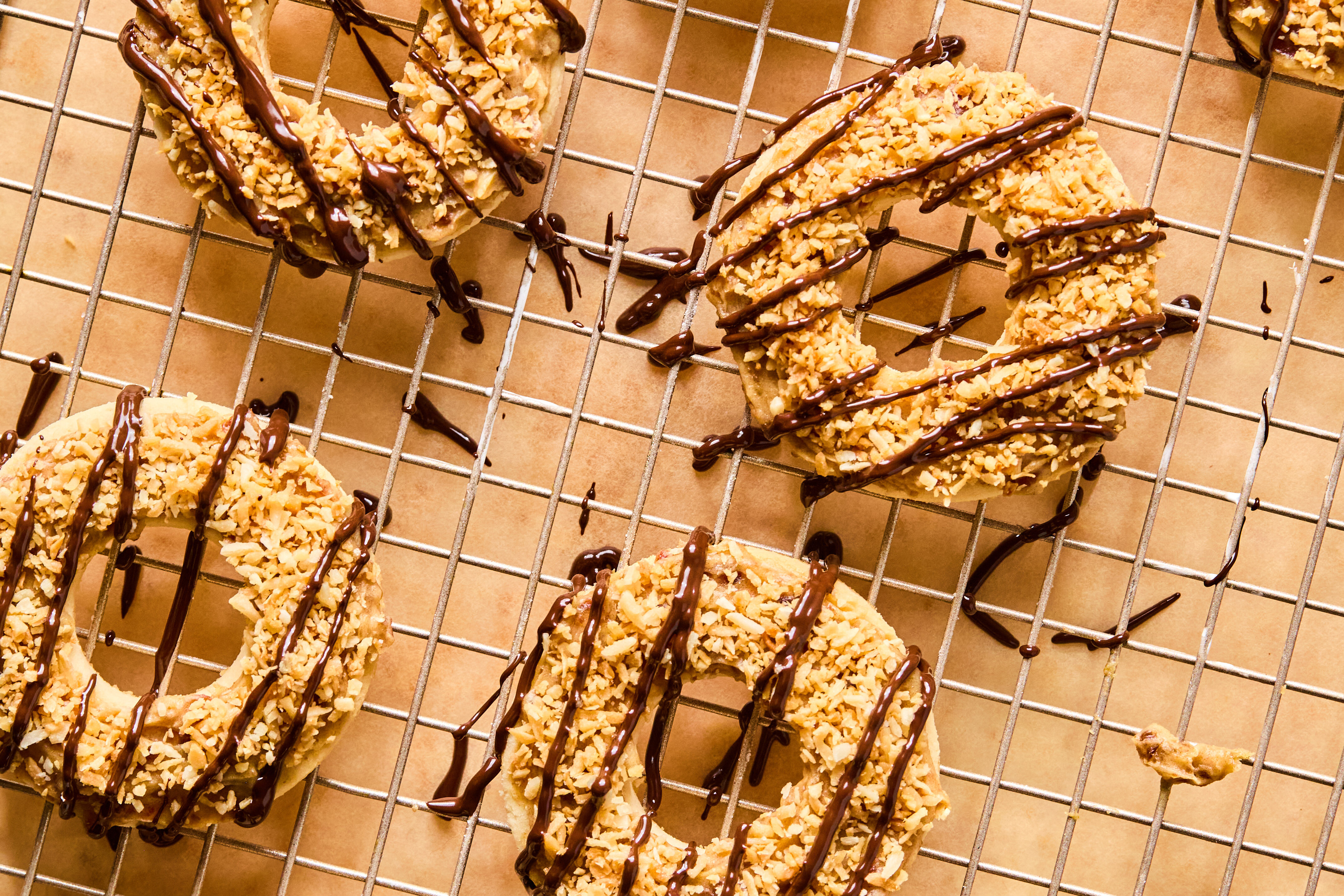Samoas on a cooling rack after being topped with date caramel, toasted caramel, and chocolate