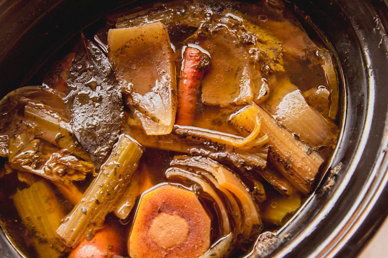 Beef bone broth cooked in a slow cooker with vegetables scraps.