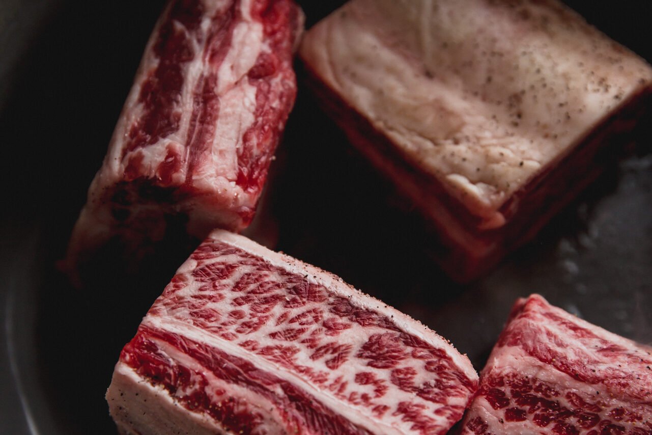 A Dutch oven with short ribs added to it to sear.