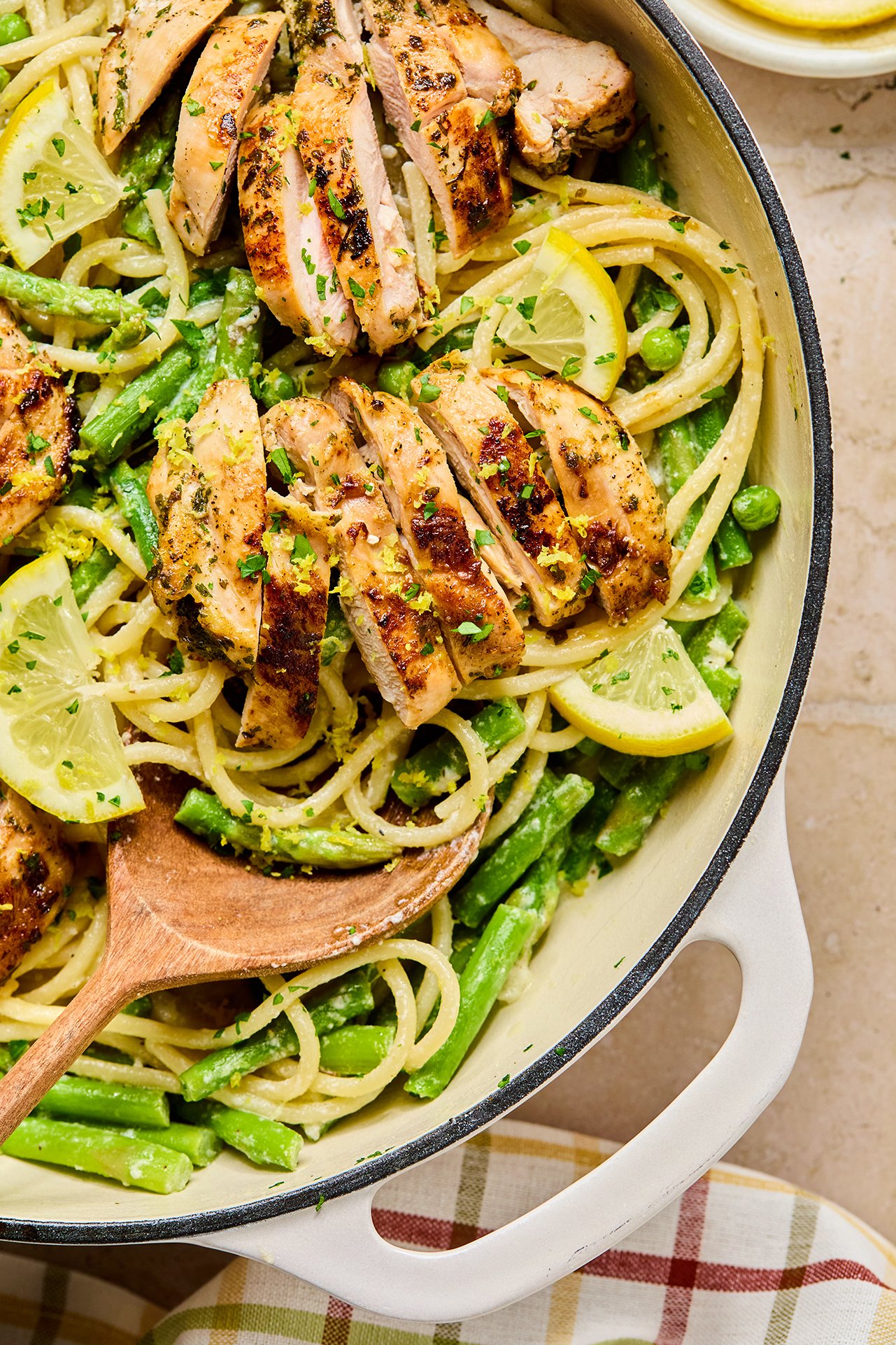 Lemon goat cheese pasta with sliced chicken thighs and green veggies in a large white pan.