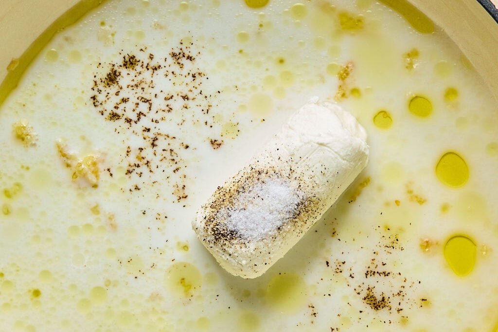 A pan with oil, garlic, goat cheese, adn lemon juice cooking to make the sauce.
