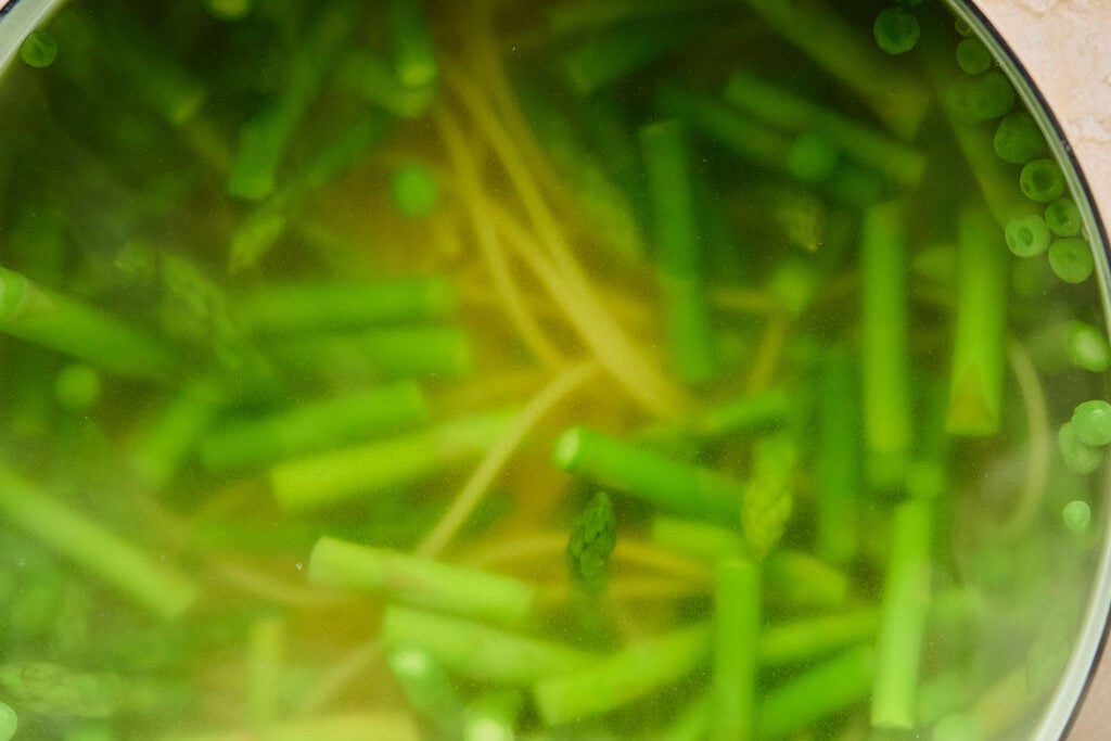 AA pot with water, pasta, asparagus and peas cooking.
