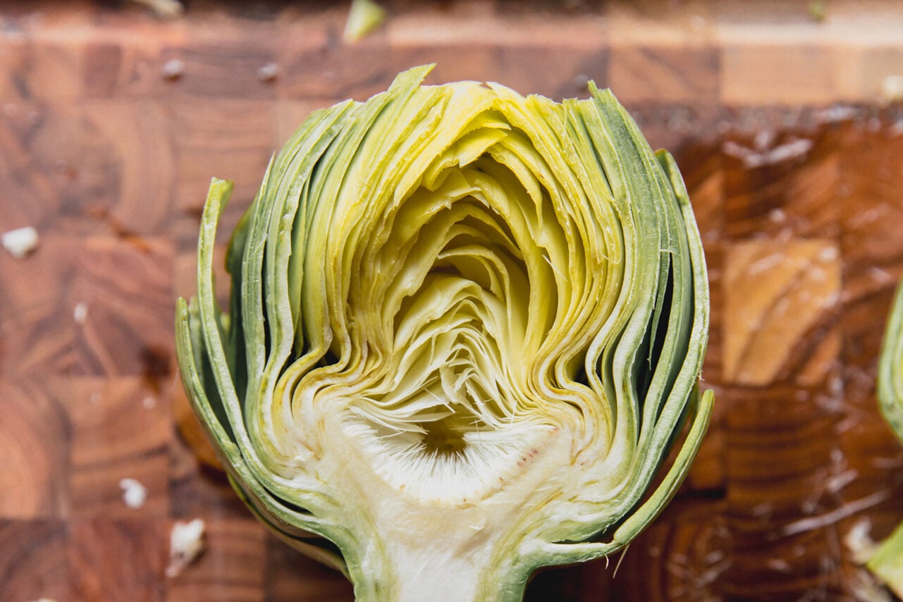 Artichoke cut in half on a cutting board.