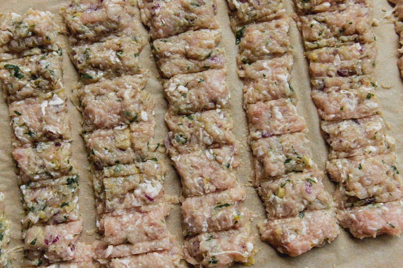 The chicken mixture pressed into an even layer on a baking sheet with scoring to mimic a kebab.