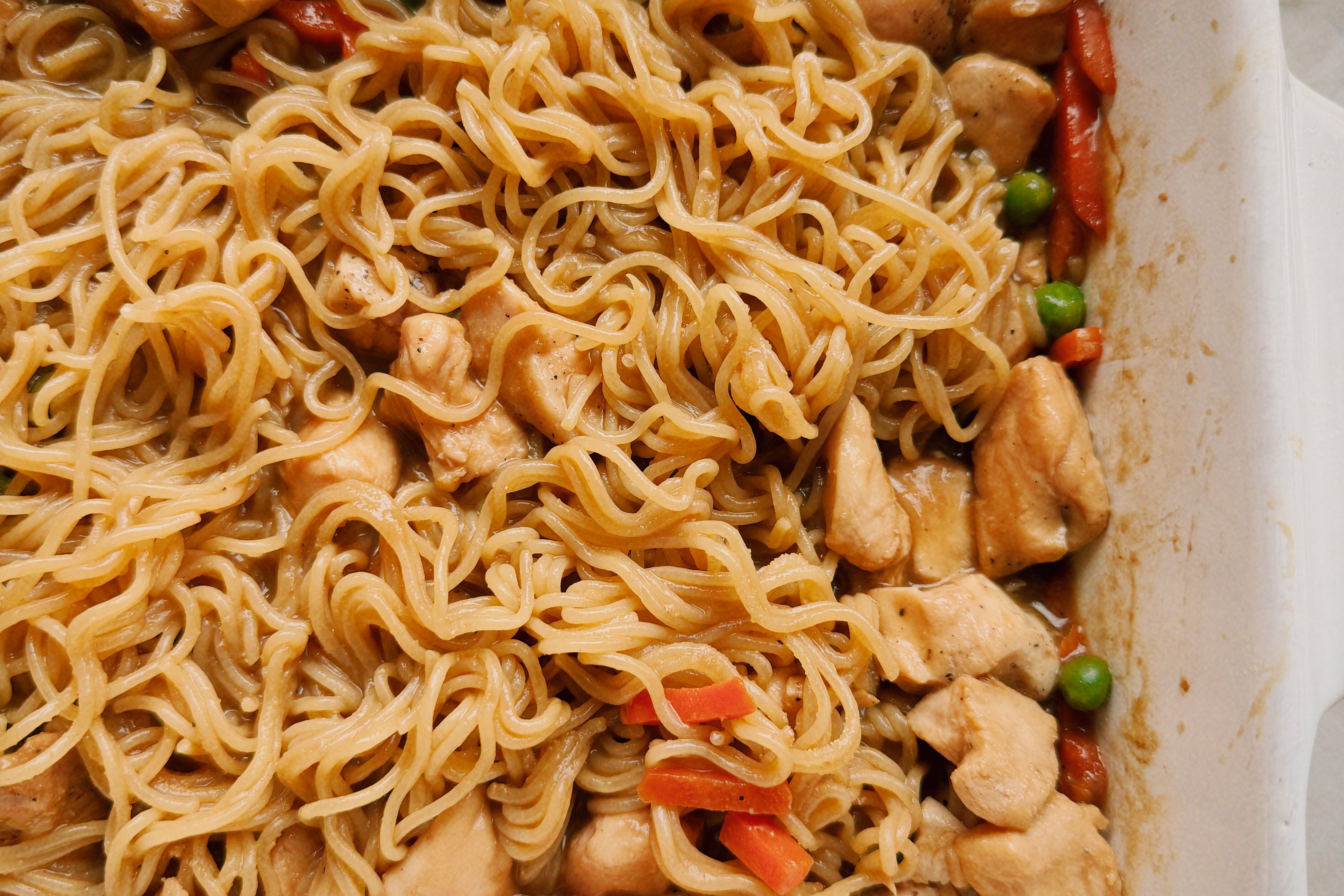 Ramen noodles in a casserole dish with chicken, veggies and sauce.