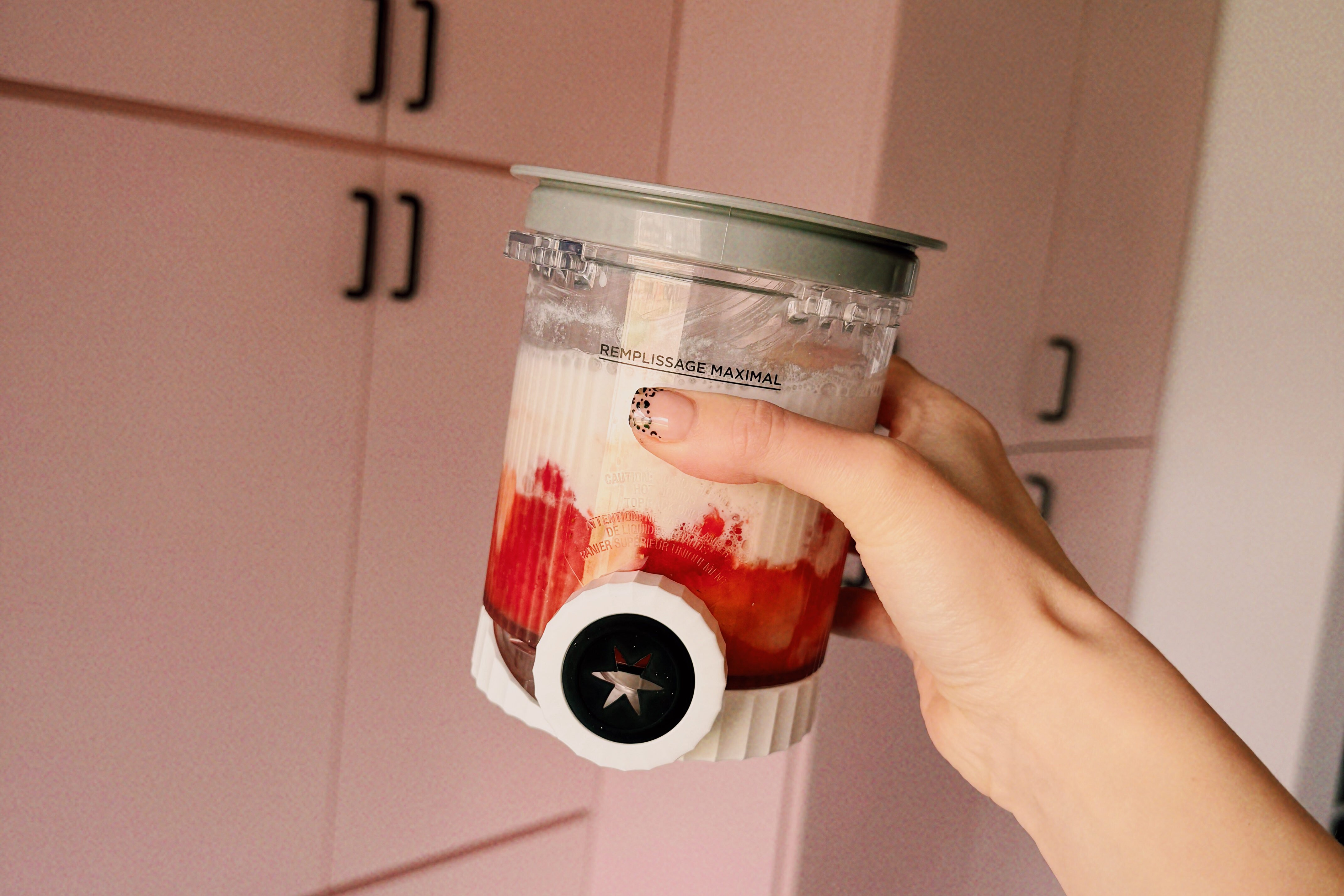 A hand holding a creami cup filled with the base of the strawberry ice cream.
