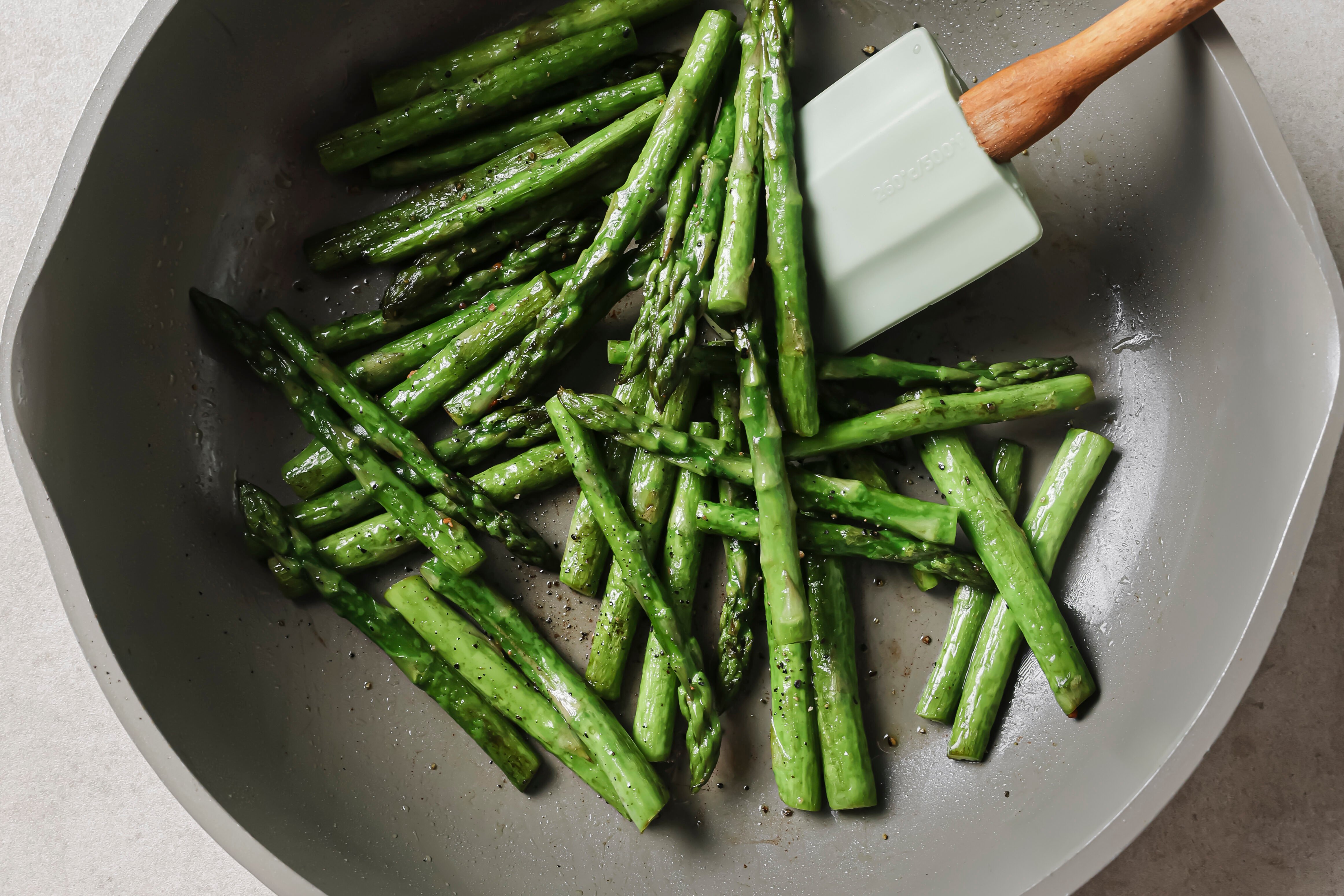 A saute pan with asparagus cooking in it.