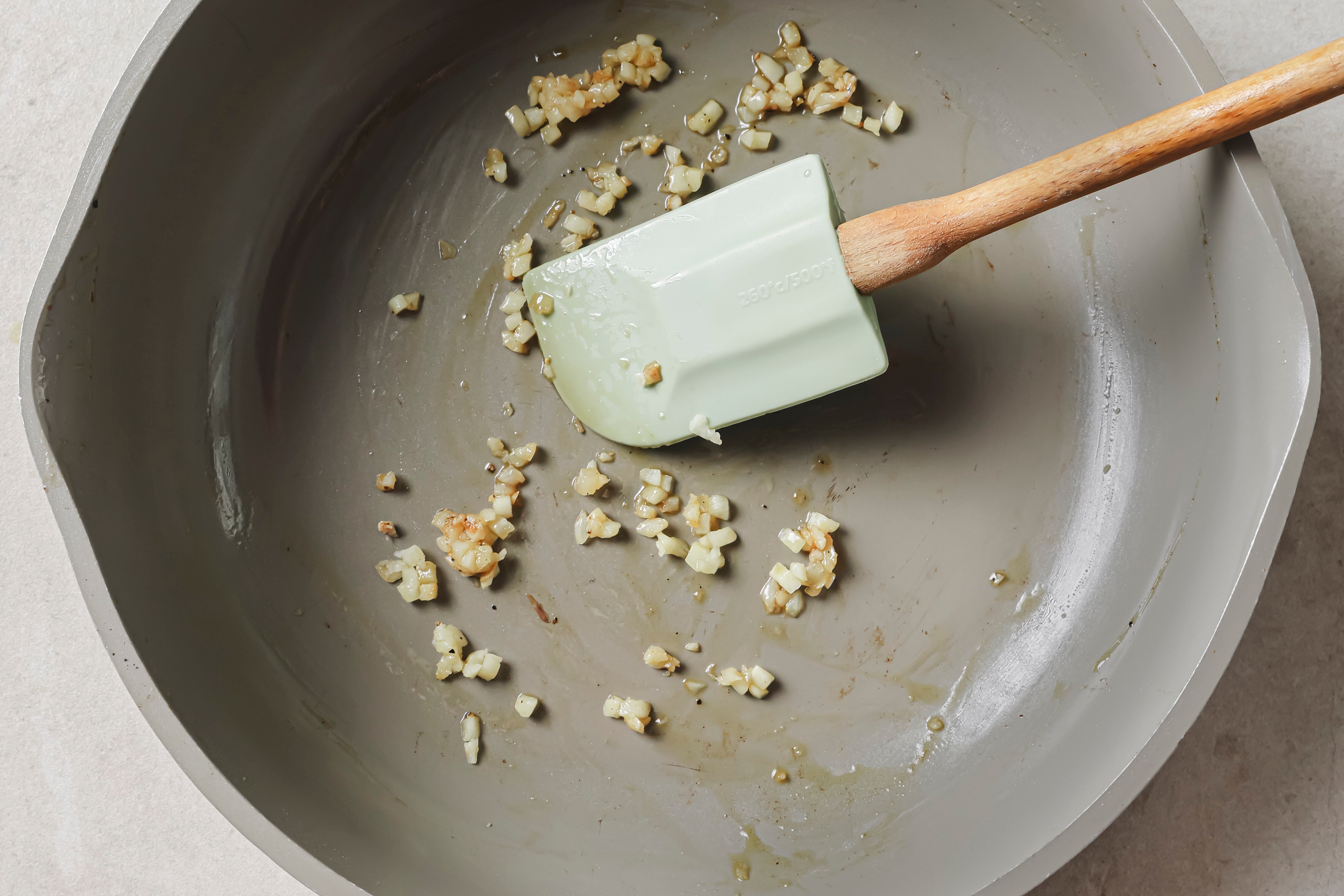Garlic sauting in a pan with a spatula.