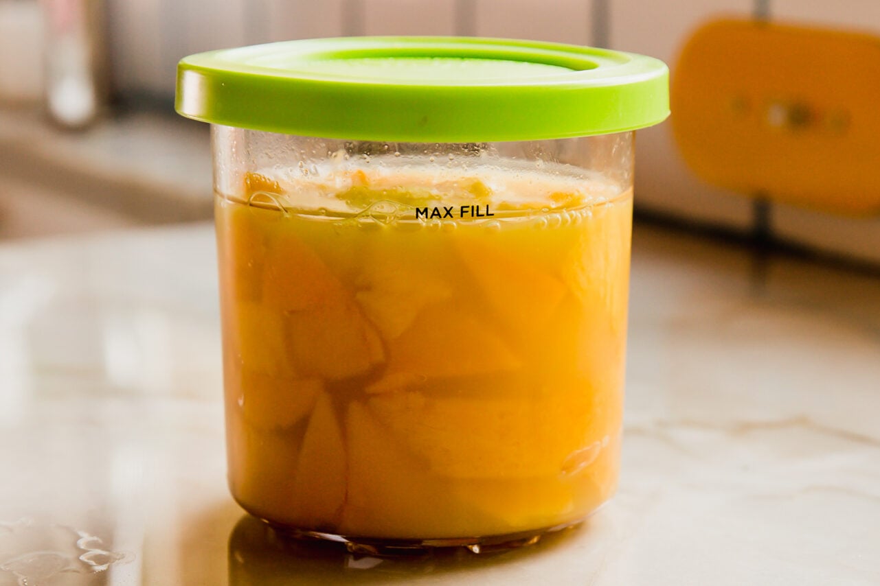 Mango and orange juice unfrozen in a ninja creami container.