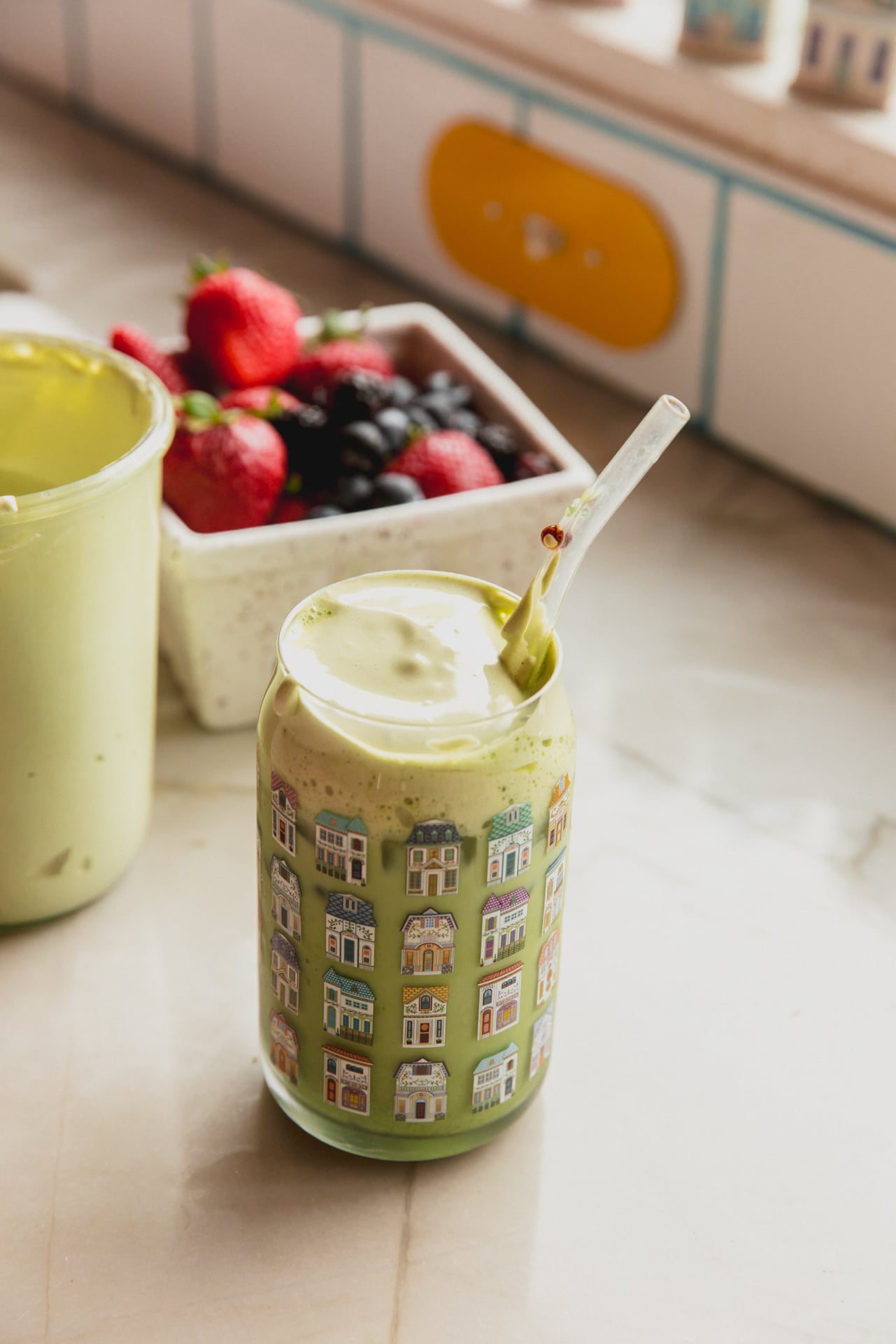 Iced matcha latte with marshmallow fluff on top and strawberries in the background.