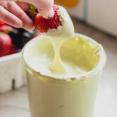 Matcha marshmallow fluff with a strawberry dipping in.