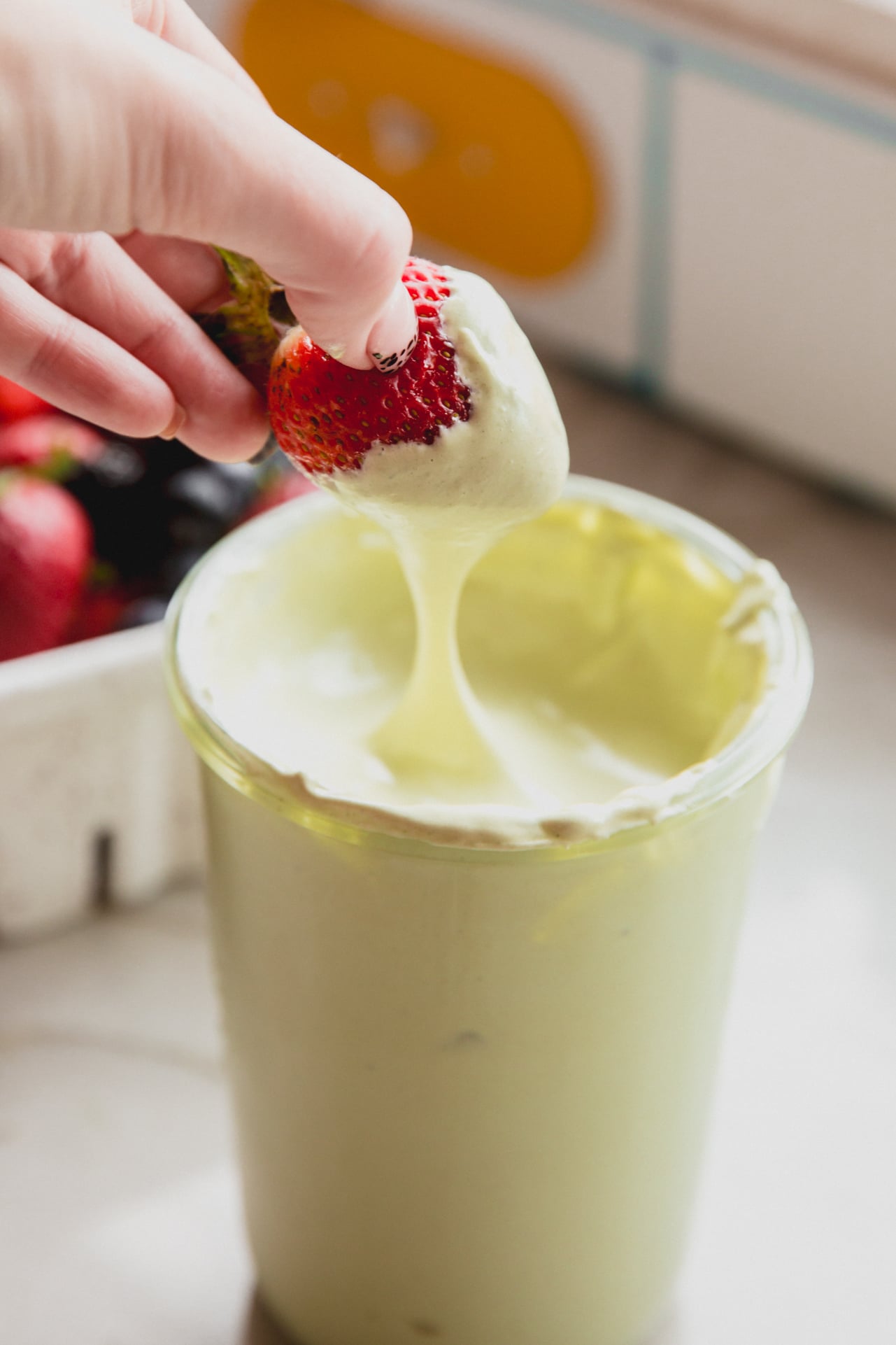 Matcha marshmallow fluff with a strawberry dipping in.