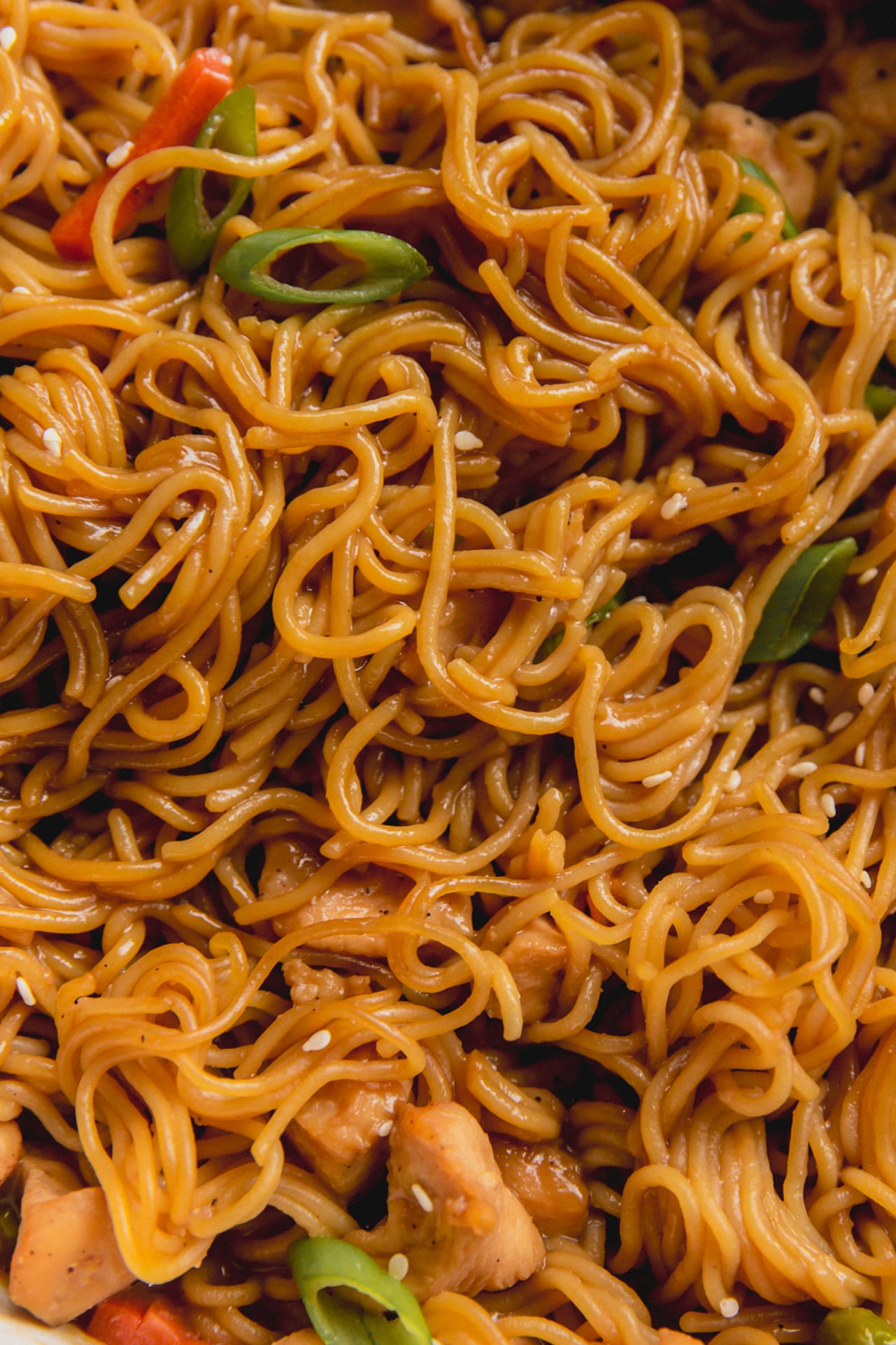 Close up of ramen noodles with chicken, veggies and sauce in a casserole dish.