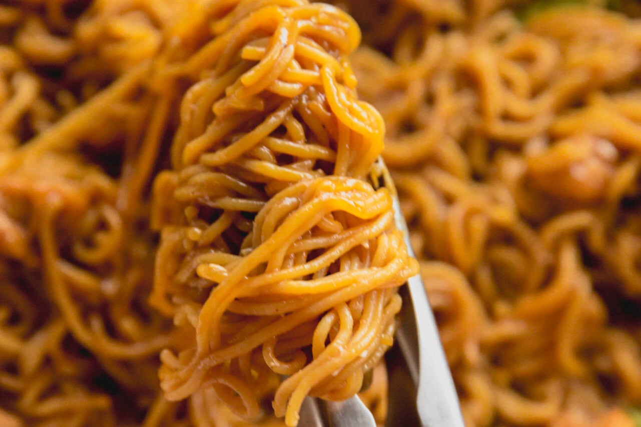 Ramen noodle bake in a casserole dish with tongs.