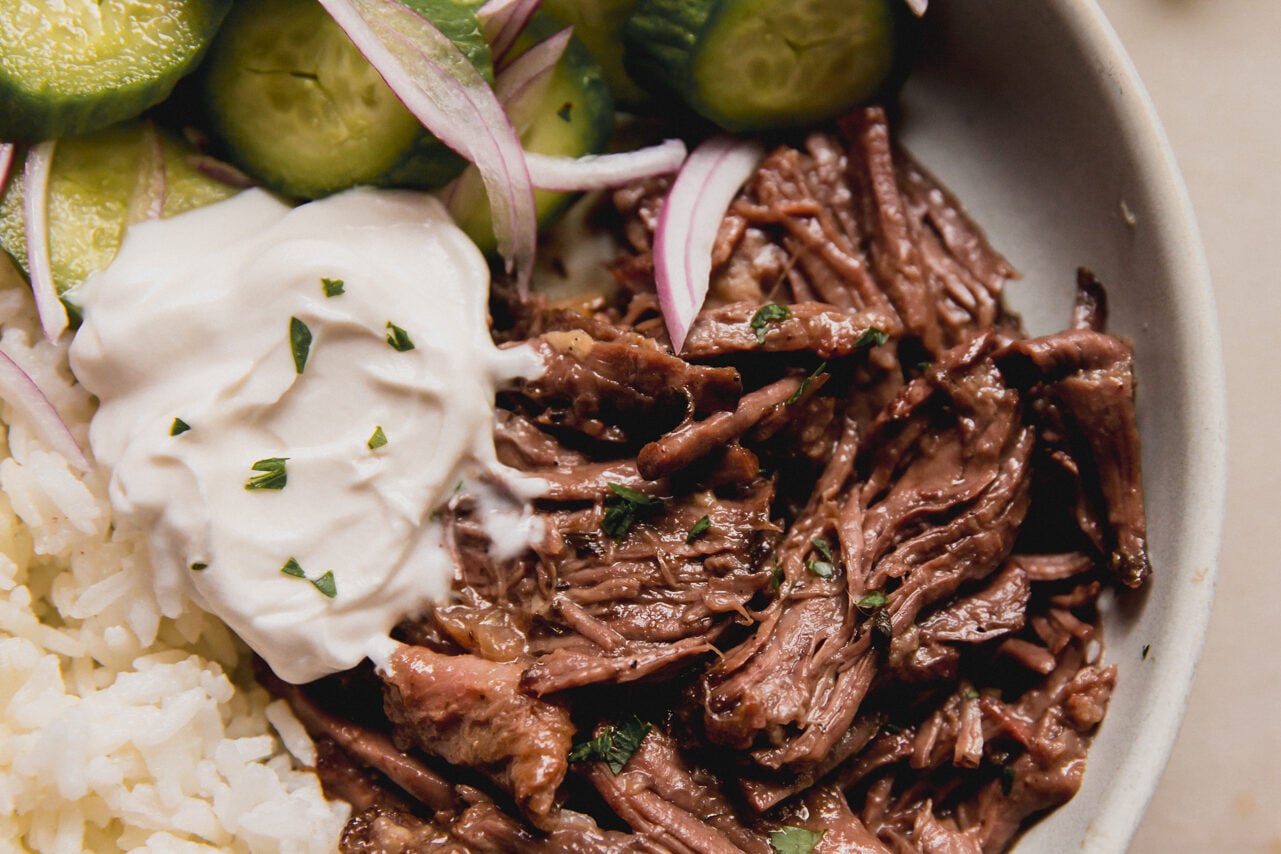 A white ceramic bowl with Mediterranean pot roast with cucumber and rice ready to be eaten.