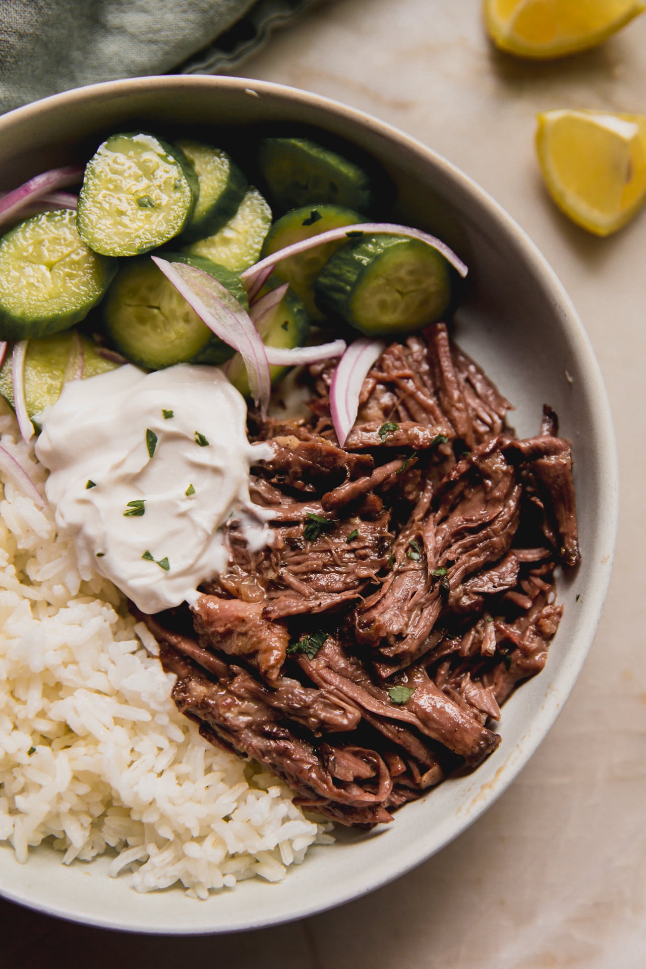 Pot roast in a bowl with rice, tzatziki and cucumber salad.