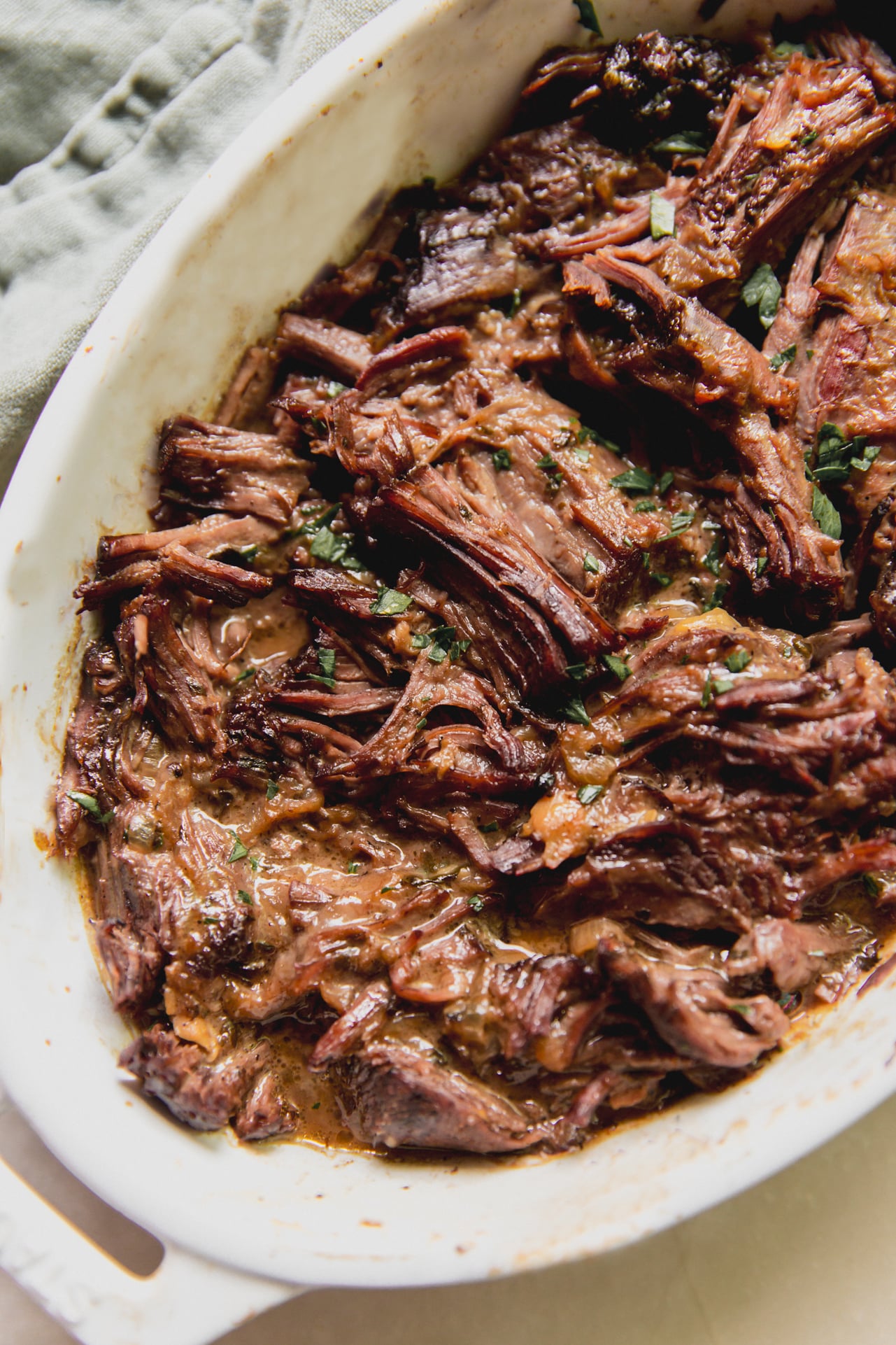 Mediterranean pot roast shredded in a large white baking dish.