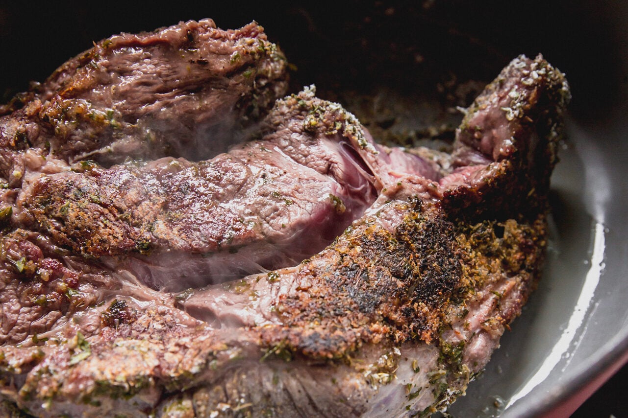 A Dutch oven with a chuck roast searing in it.