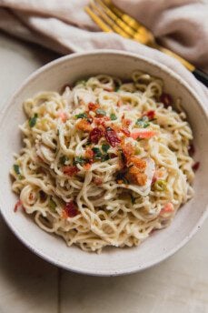 A serving of bacon ranch ramen bake in a bowl topped off with parsley and bacon.