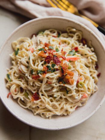 A serving of bacon ranch ramen bake in a bowl topped off with parsley and bacon.
