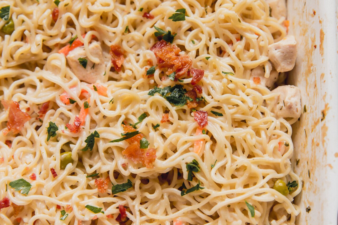 Bacon ranch ramen bake topped with parsley and bacon in a large casserole dish.