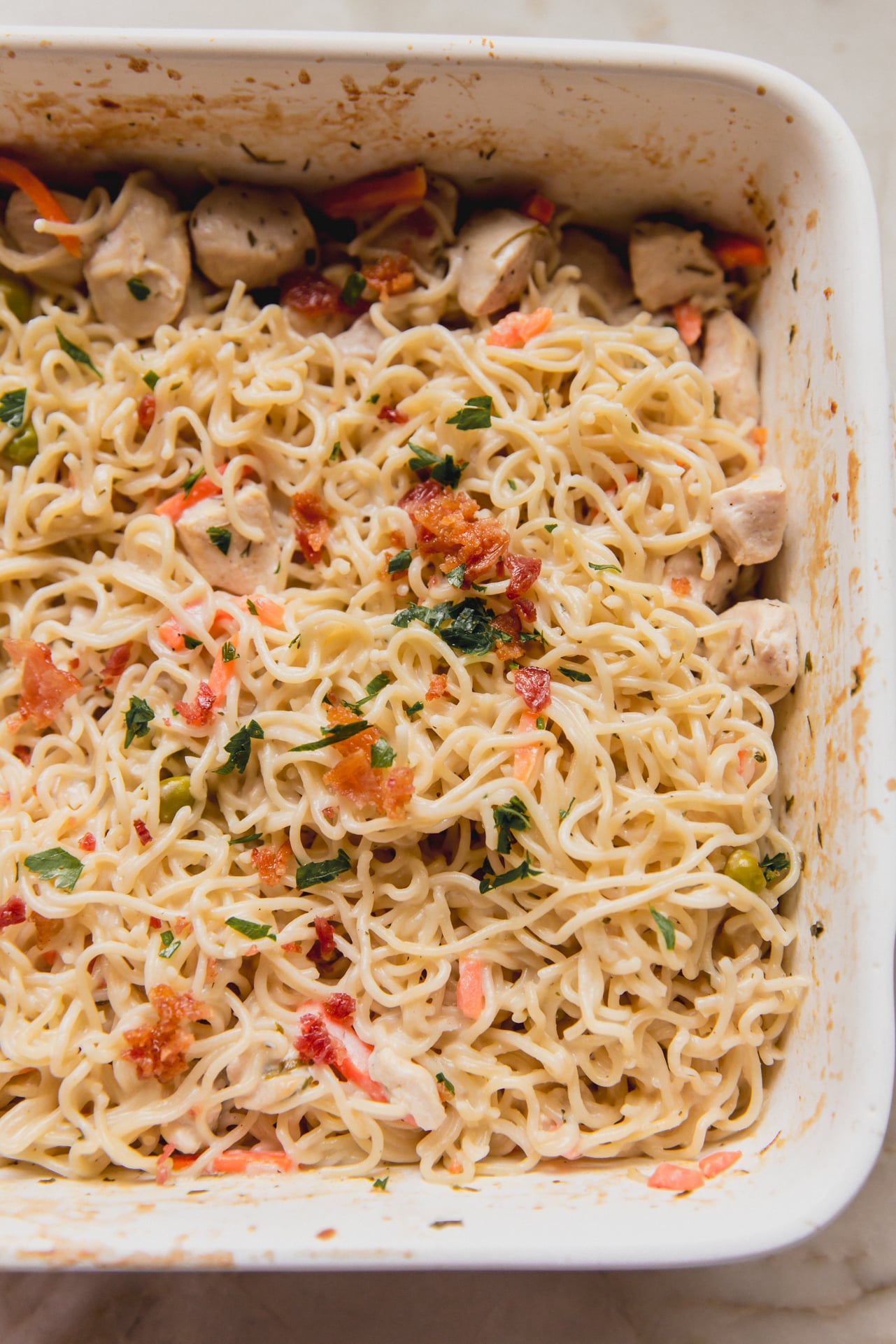 Bacon ranch ramen bake topped with parsley and bacon in a large casserole dish.