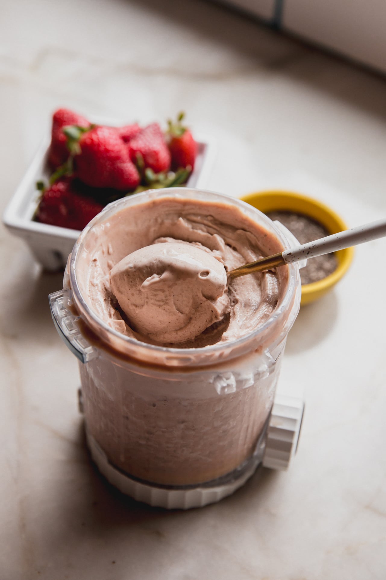 A ninja creami pint container of chia seed ice cream after spinning witha spoon taking a spoonful out.