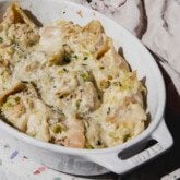 Creamy chicken stuffed shells topped with parsley with an oval baking dish.