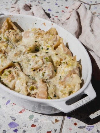 Creamy chicken stuffed shells topped with parsley with an oval baking dish.