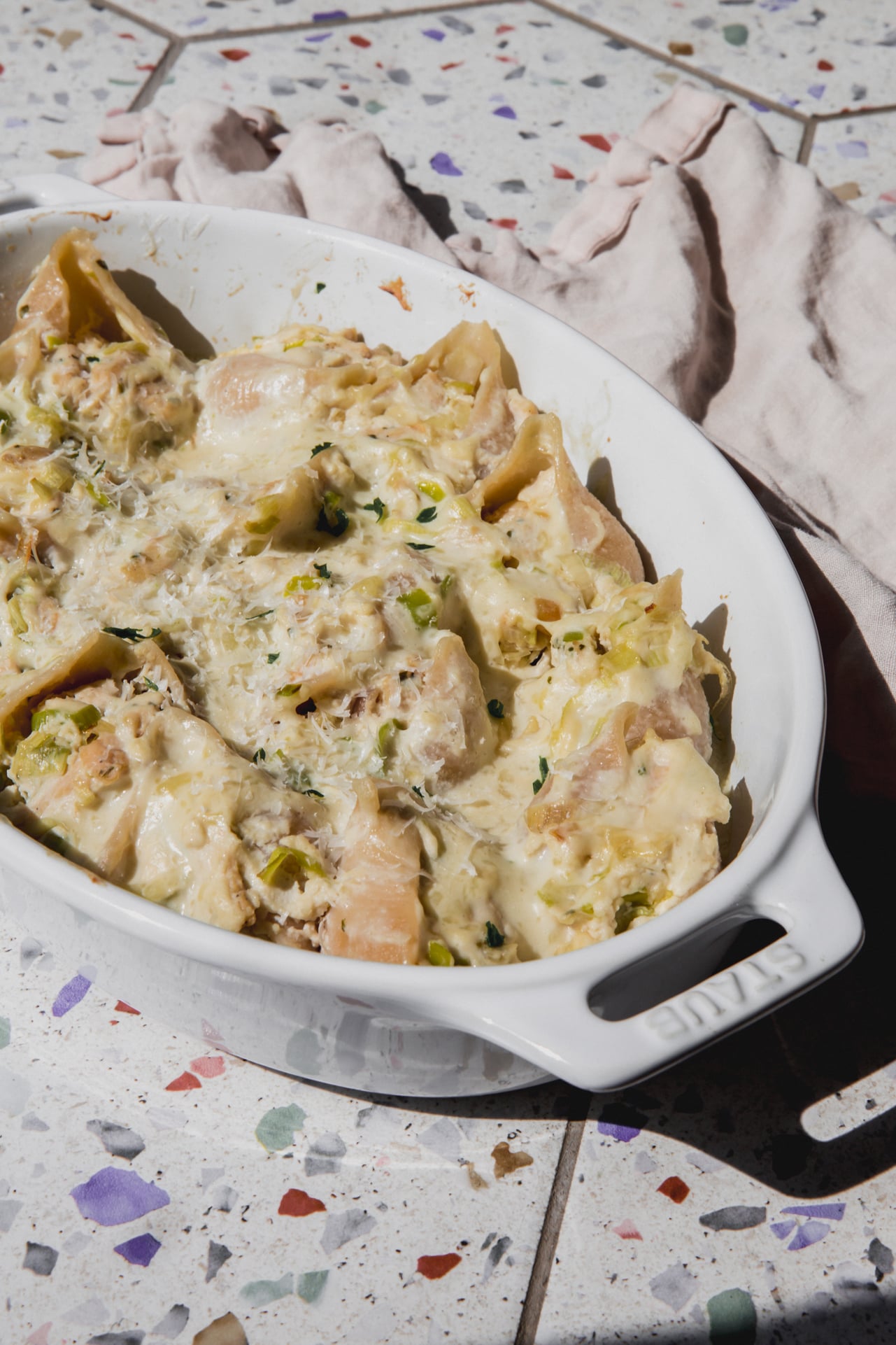 Creamy chicken stuffed shells topped with parsley with an oval baking dish.