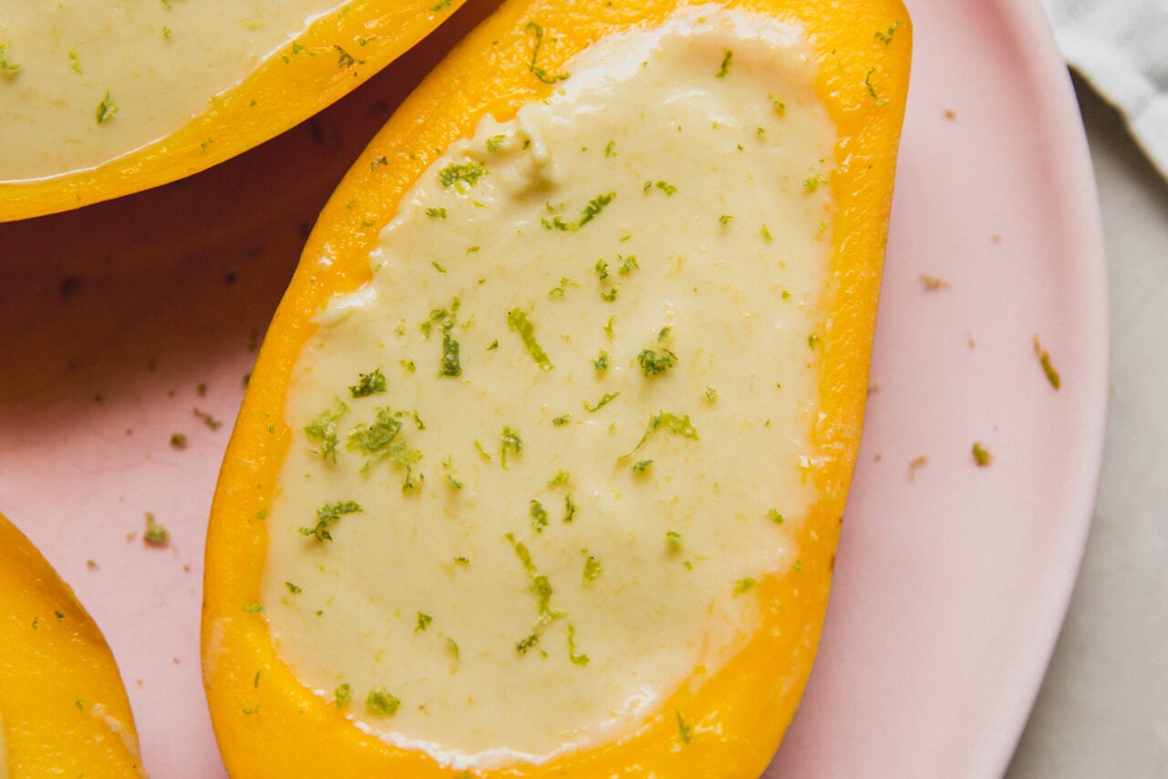 Mango posset topped with lime zest sitting on a pink plate.