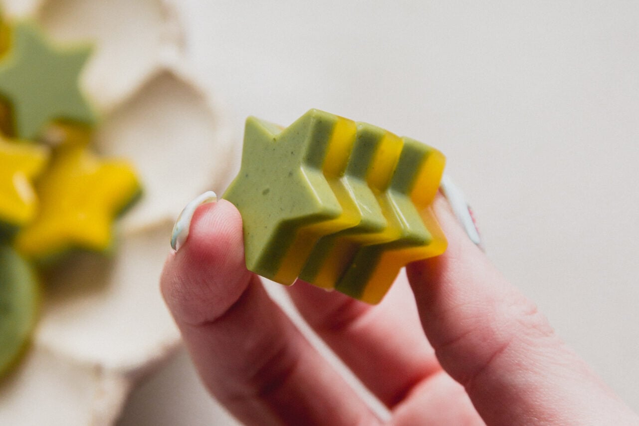 A hand holding mango matcha gummies in it.