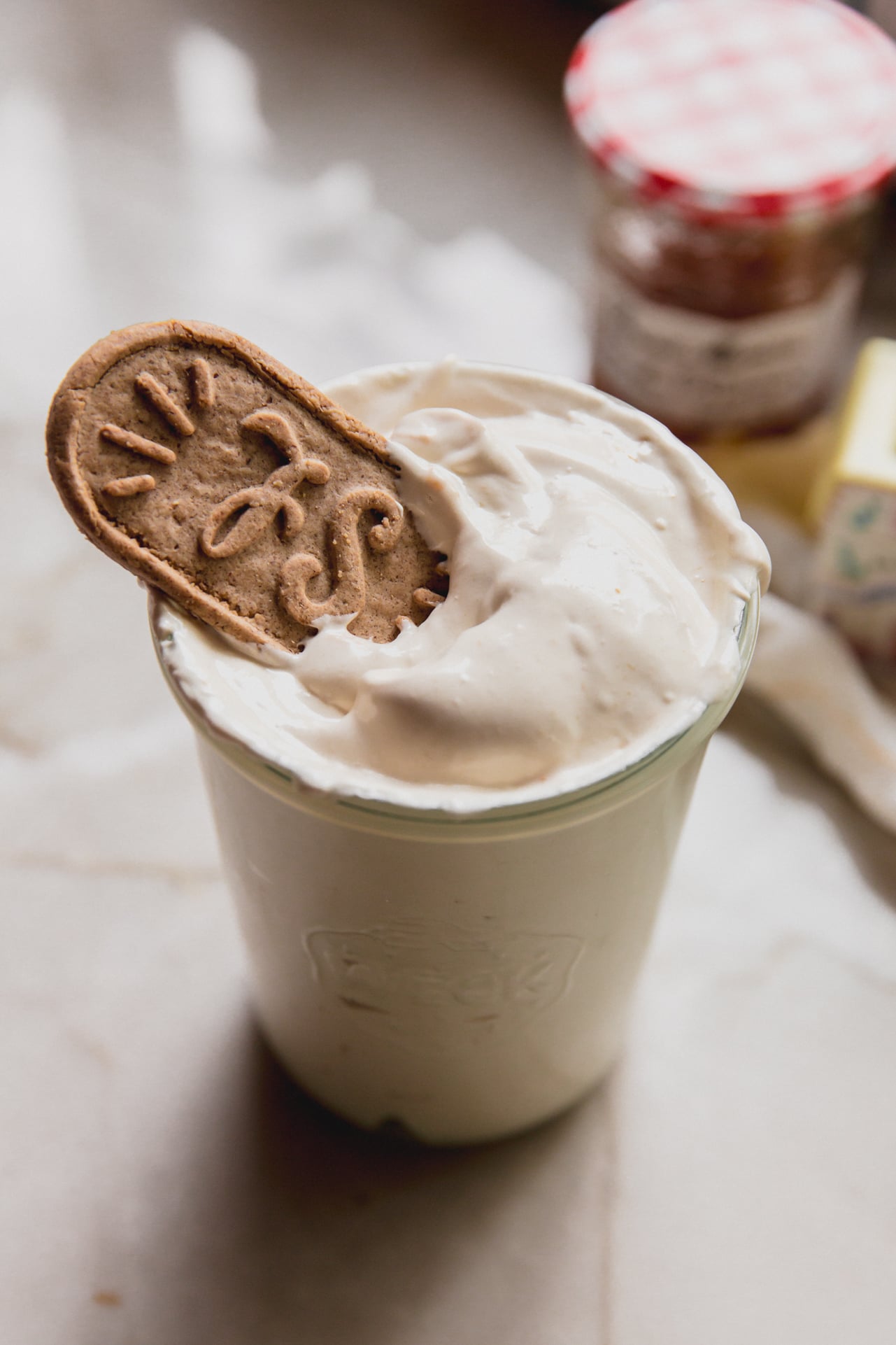A glass cup filled with peach vanilla marshmallow fluff with a biscoff cookie on top.
