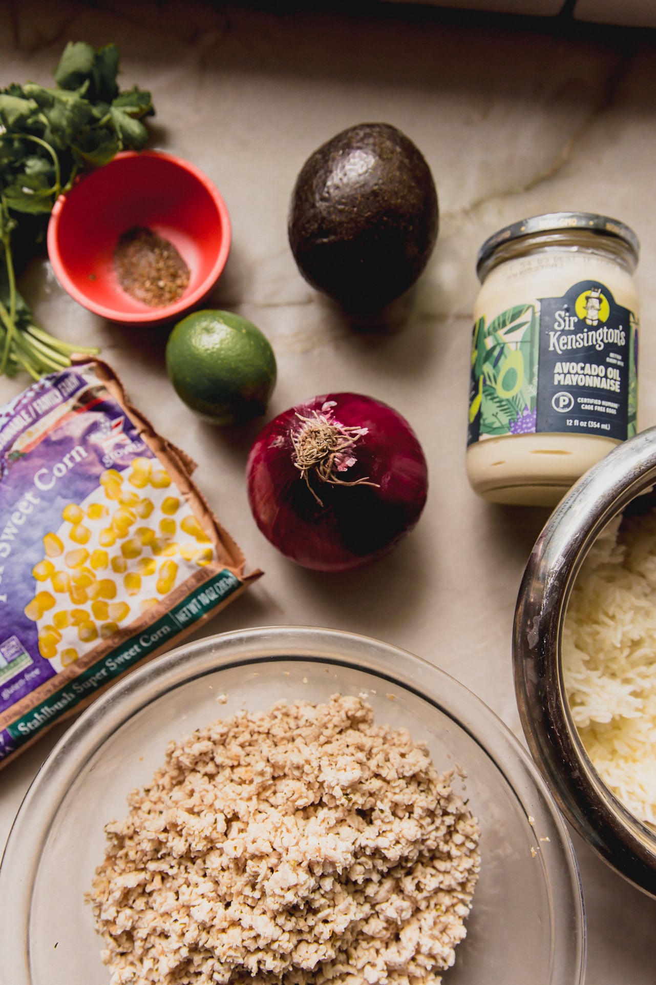 All the ingredients to make street corn ground chicken bowls laid out on a counter.