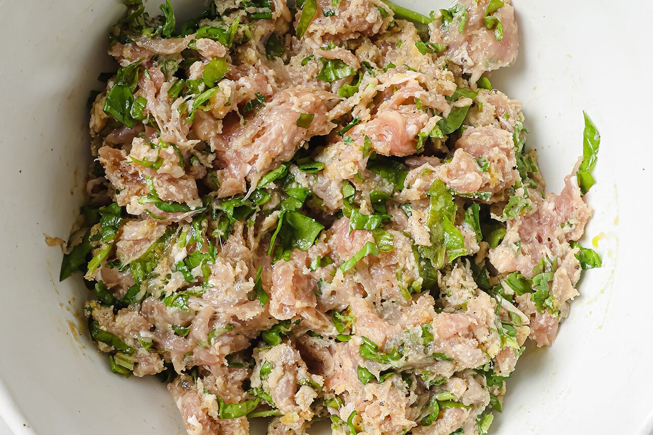 Ground chicken, spinach and herbs mixed in a bowl.