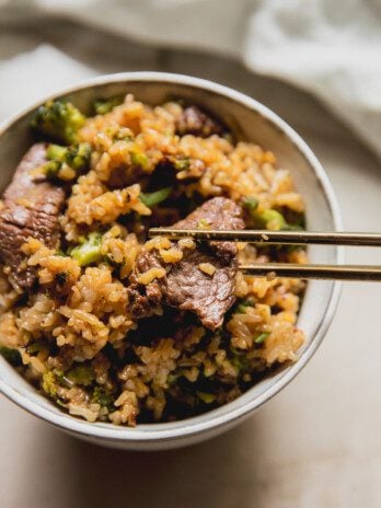 Beef and broccoli ramen in a small white bowl with chopsticks.