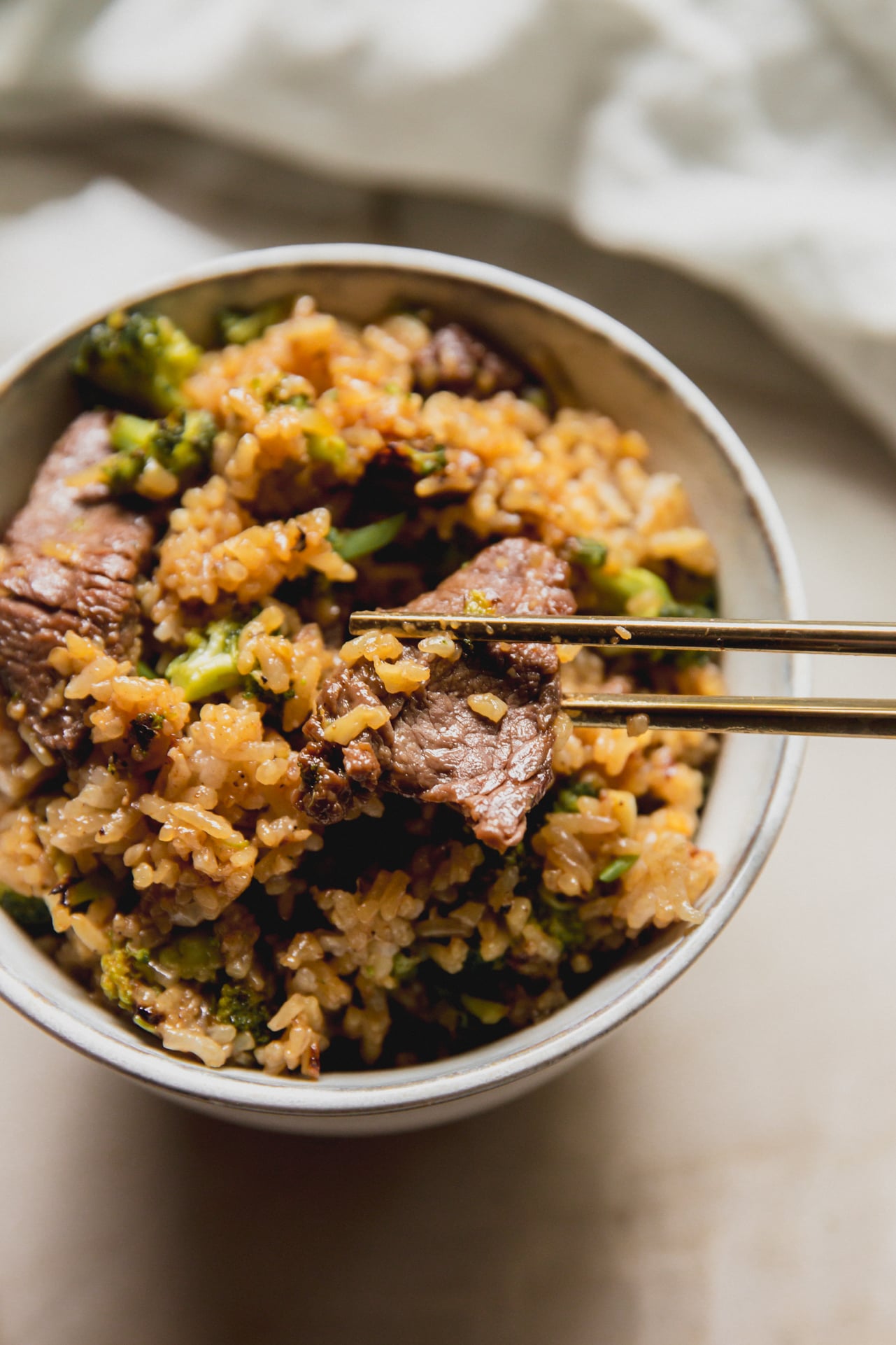 Beef and broccoli ramen in a small white bowl with chopsticks.